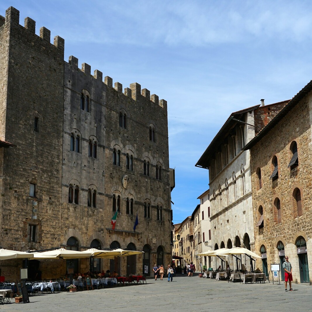 a street lined with tables and chairs next to tall buildings