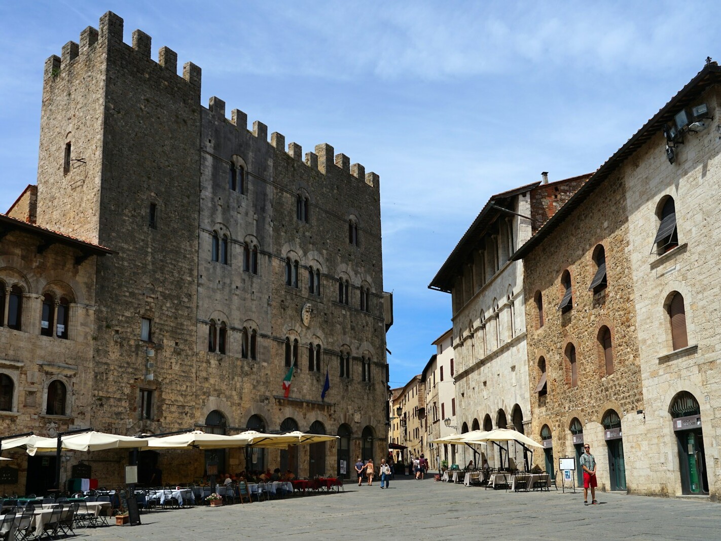 a street lined with tables and chairs next to tall buildings