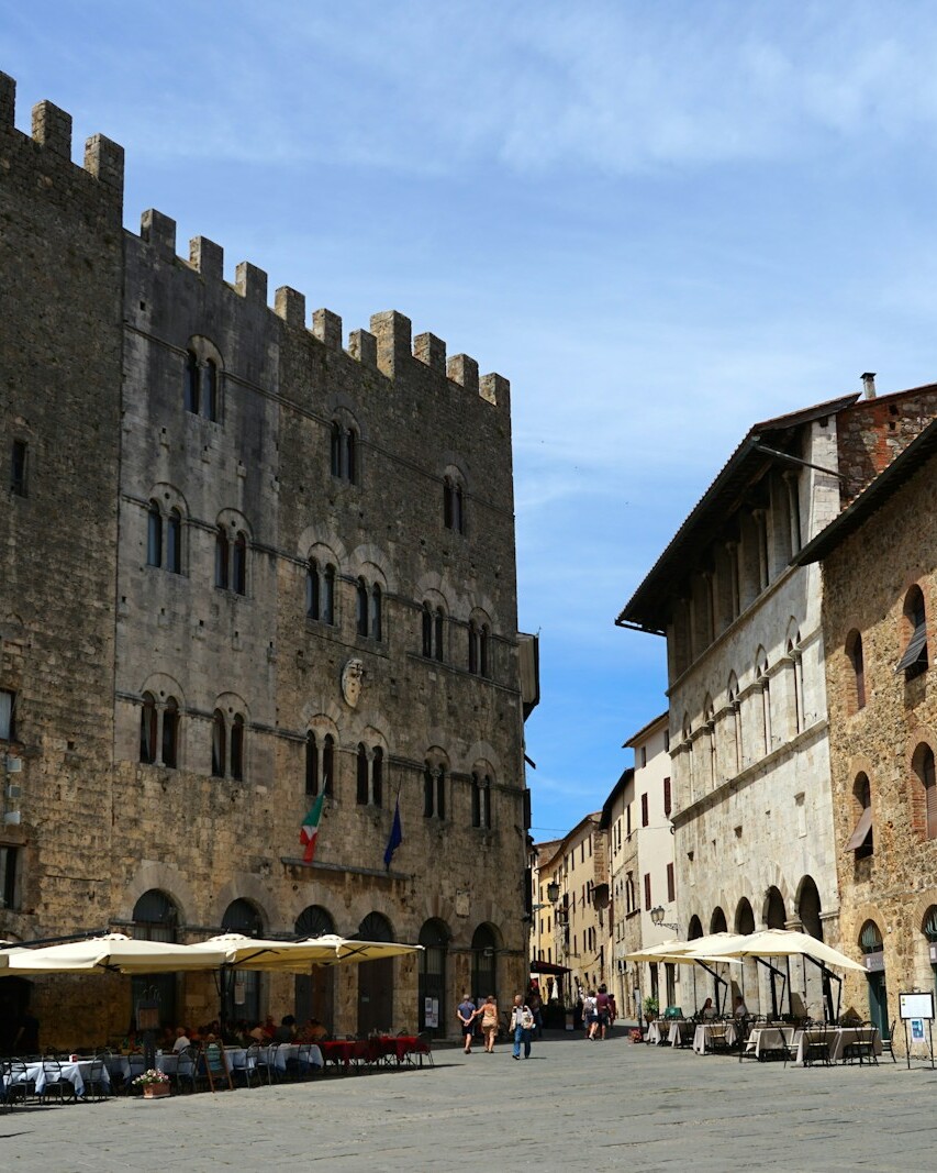 a street lined with tables and chairs next to tall buildings